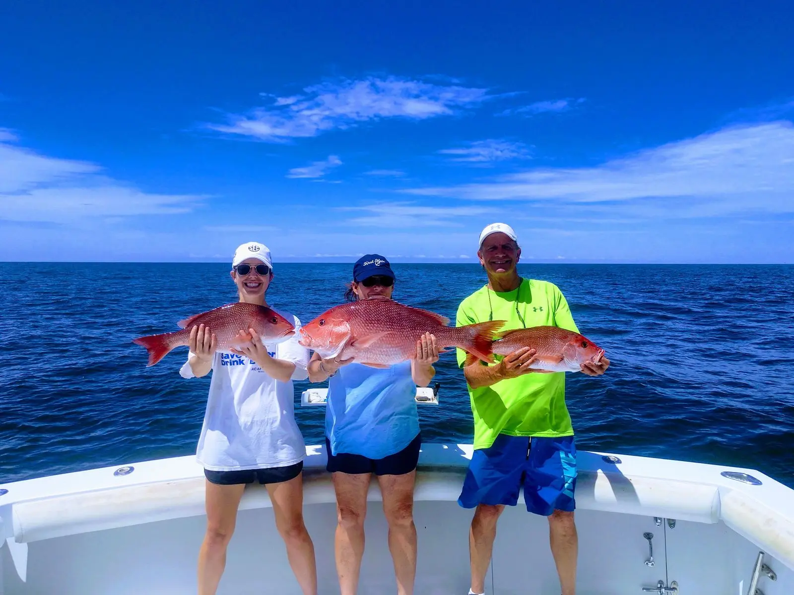 Three anglers displaying red snapper caught offshore from Orange Beach