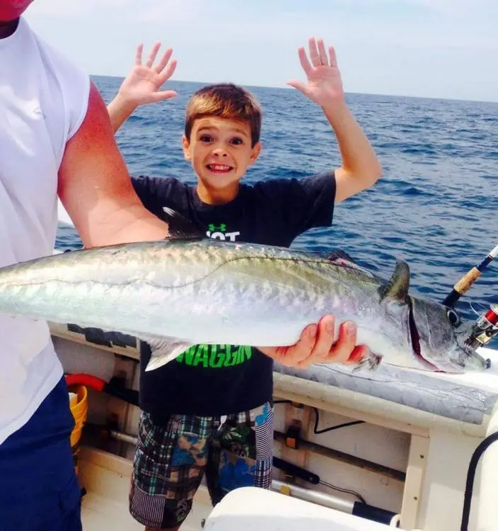 Young angler holding a wahoo aboard Hooked Up Fishing Charters